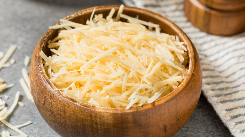 Shredded parmesan cheese in a small wooden bowl