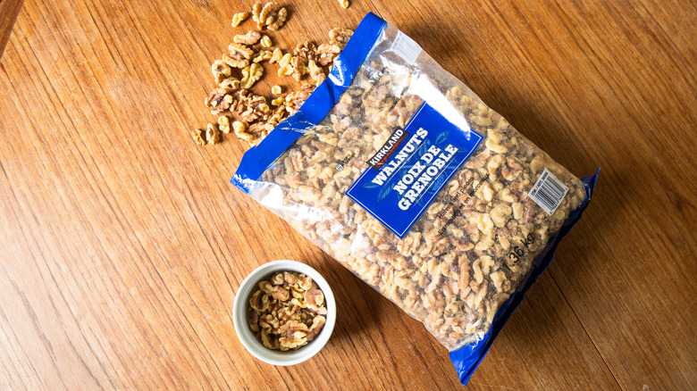 A bag of Kirkland Signature Shelled Walnuts beside a ramekin with nuts.