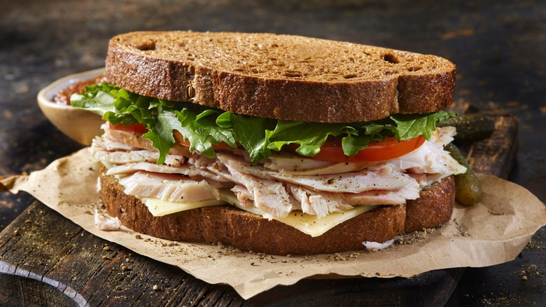 turkey sandwich with rye bread, lettuce, and tomatoes