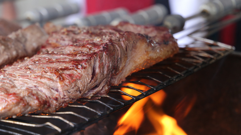 A flank steak on a grill with flames