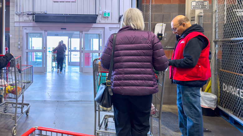 Costco employee checking a customer's receipt at the exit of the store
