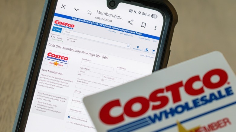 A Costco membership card sitting on top of a phone with the Costco membership login page open.