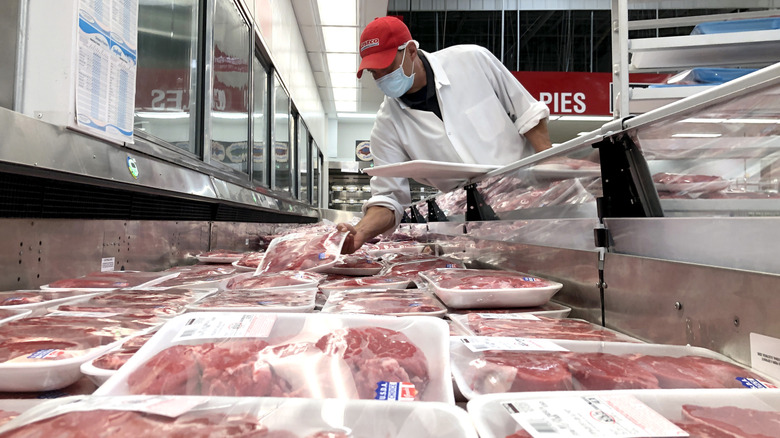 Costco butcher counter with employee stocking steak