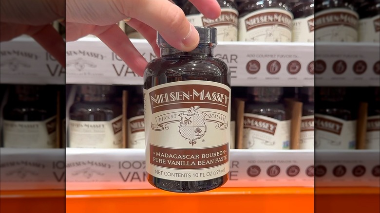 Hand holding a 10-ounce bottle of Nielsen-Massey Madagascar Bourbon Vanilla Bean Paste at Costco.