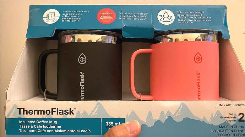 Hand holding Costco's ThermoFlask Drinkware Insulated Coffee Mug with Handle two-pack in black and pink.