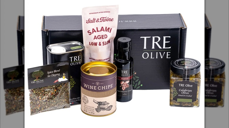 Selection of specialty olive oil products by TRE Olive in front of packaging box.