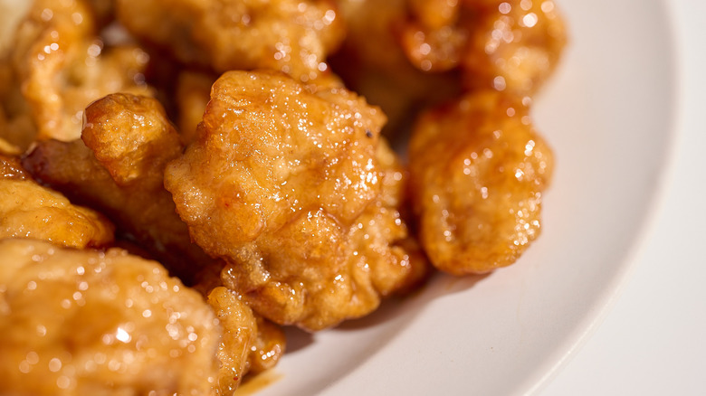 A close up of cooked orange chicken on a plate