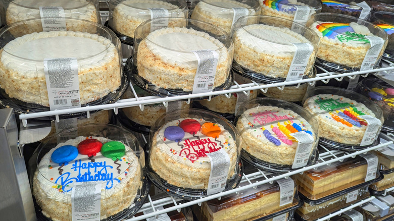 Decorated vanilla cakes lined up on a Costco bakery shelf.