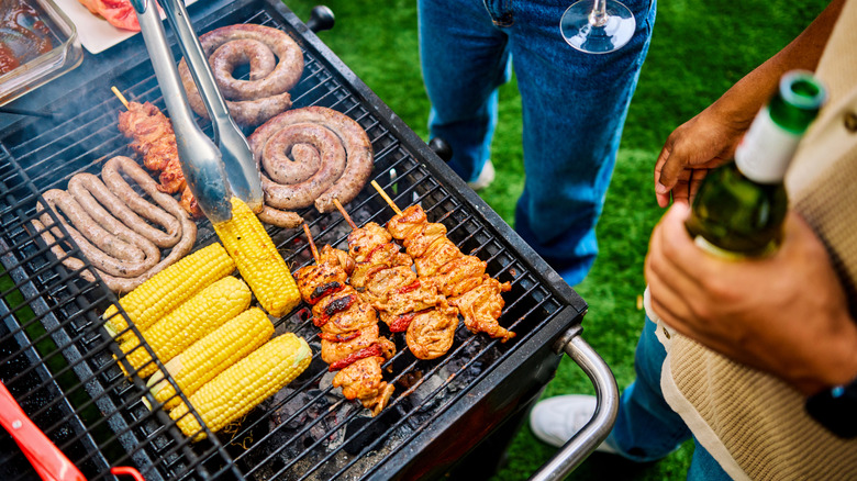 Assorted meats and corn being barbecued on an outdoor grill