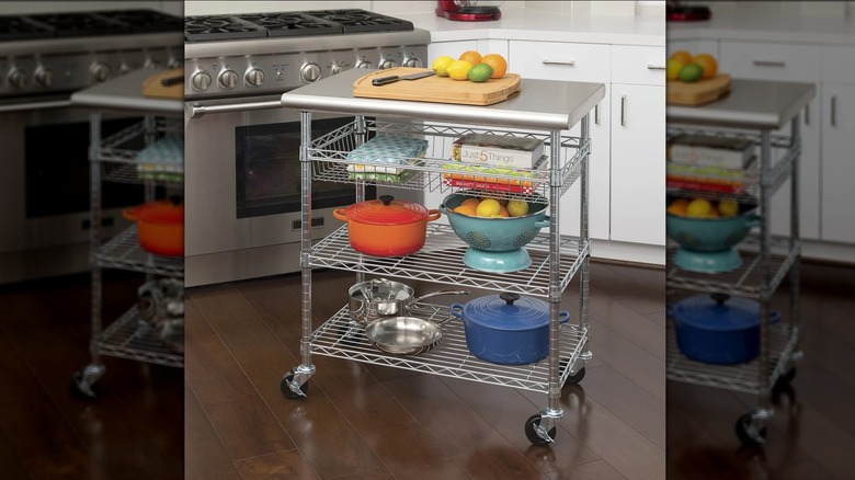 A Seville Classics stainless steel kitchen cart in a display photo, loaded up with items like cookbooks and pots.