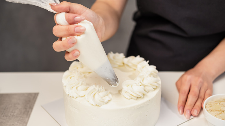 Woman icing a white cake