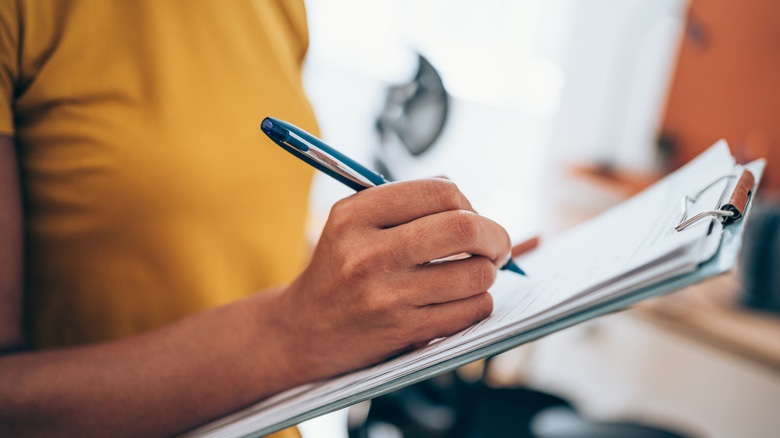 Person filling out clipboard form