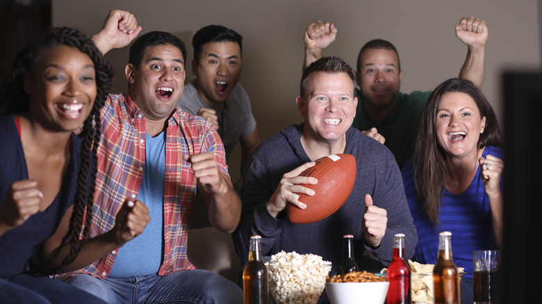 A group of friends cheers at a Super Bowl party.