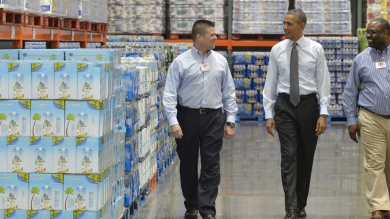 President Barack Obama walking down the aisle of a Costco in between two Costco staff members