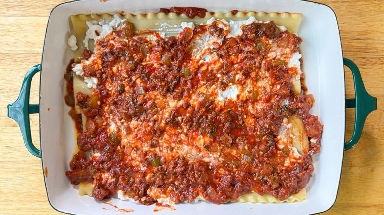 Beef lasagna sauce over cottage cheese and lasagna noodles in 13 x 9-inch pan