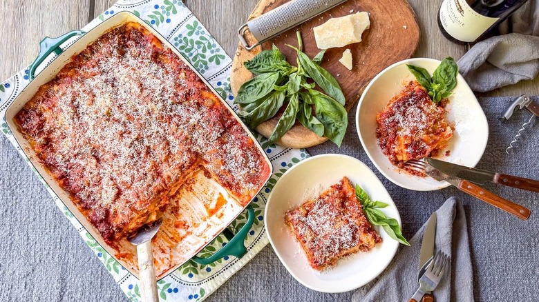 Cottage cheese lasagna in serving pan and sliced in bowls with fresh basil, parmesan, and grater