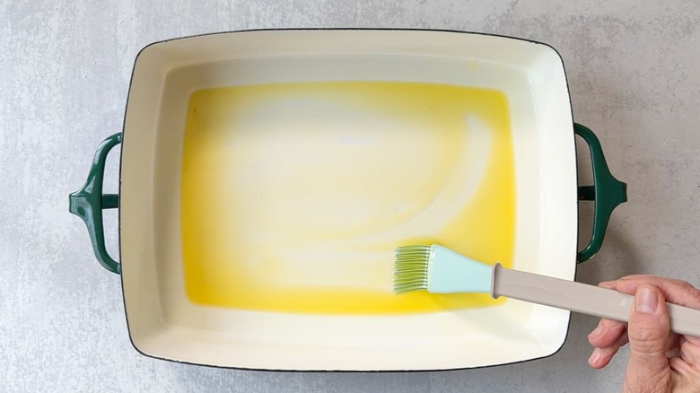 Brushing oil onto a 13 x 9-inch baking dish with a pastry brush