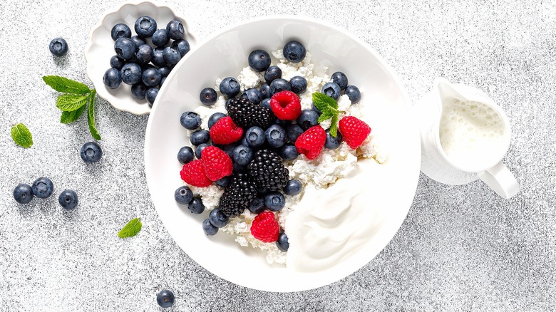 White bowl with yogurt, cottage cheese, and mixed berries