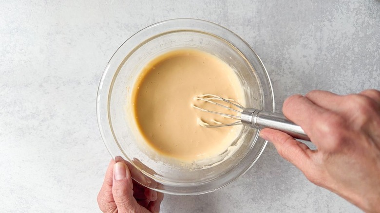 Whisking together lemon-soy aioli ingredients in glass bowl