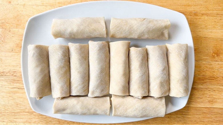 Raw crab cake egg rolls on white platter
