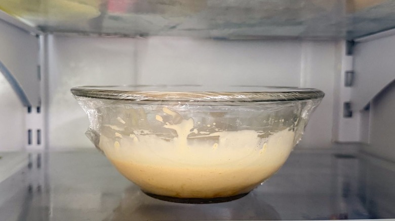 Lemon-soy aioli in plastic-covered glass bowl in refrigerator