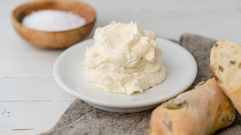 Whipped butter on a plate next to sliced rustic bread