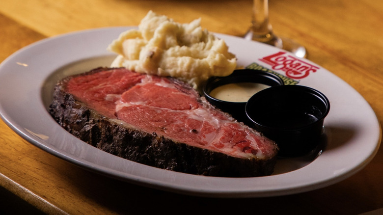Close-up of Logan's Roadhouse prime rib plate with mashed potatoes and sauces
