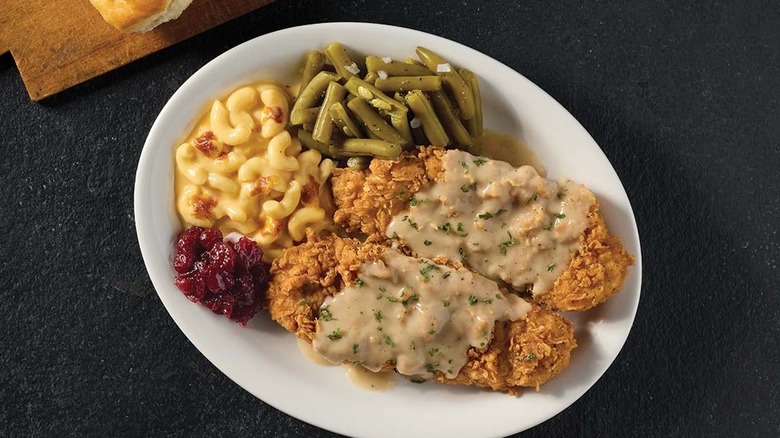 Country fried turkey with gravy, green beans, mac and cheese, and cranberries on a white plate from Cracker Barrel