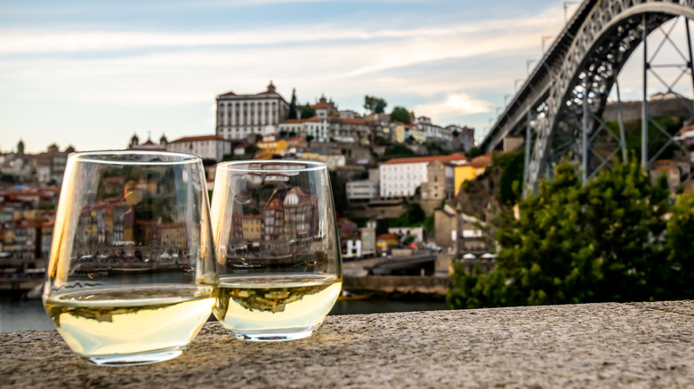 Two glasses of white wine with Portugese city and iron bridge in background