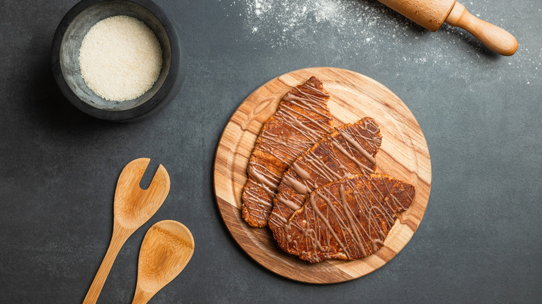 Three flat croissants served on a wooden plate
