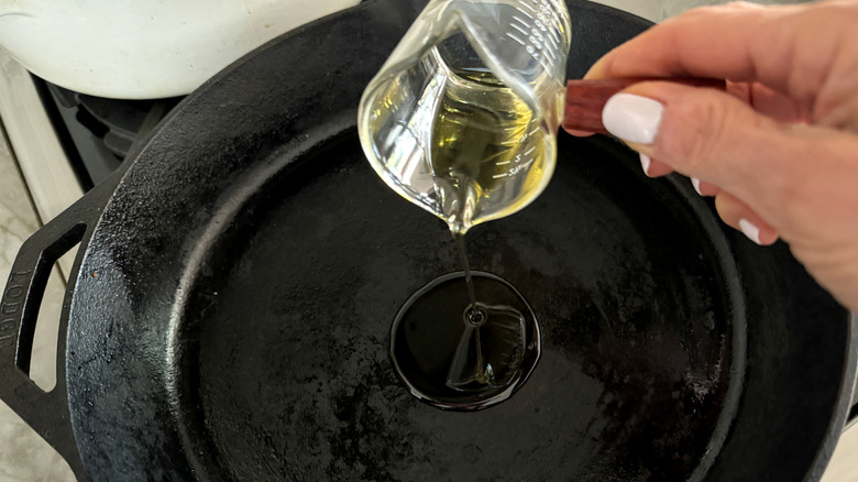 hand adding oil to skillet
