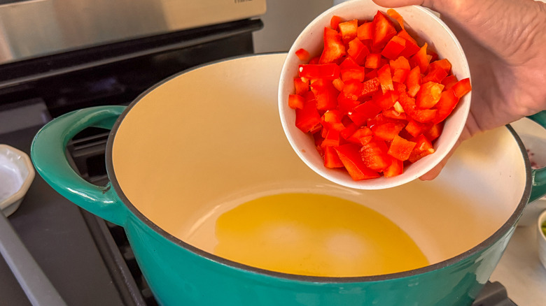 hand adding red pepper to pot