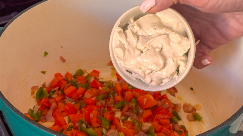 hand adding cream cheese
