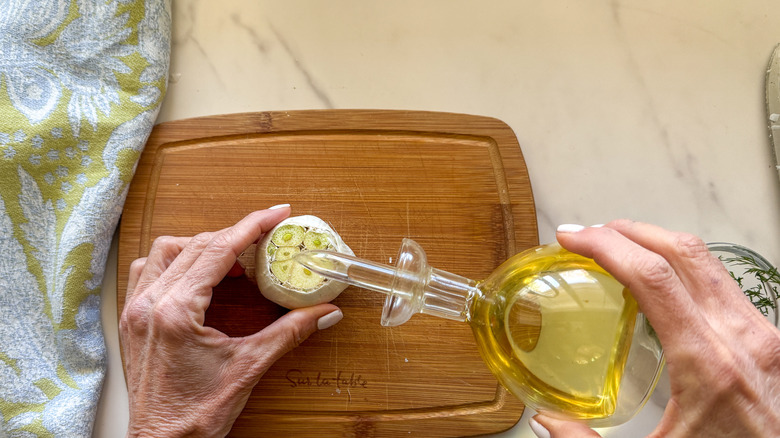 hand pouring oil on garlic