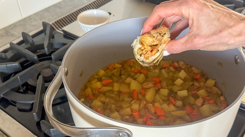 hand holding garlic over pot