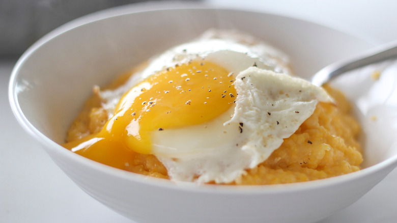 A bowl of grits with a fried egg on top.