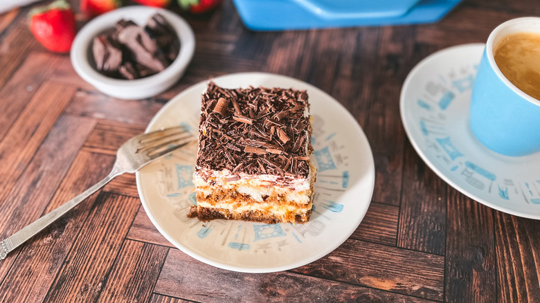 Creamy hazelnut tiramisu slice on plate with coffee and chopped chocolate