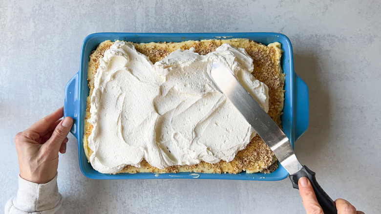 spreading whipped cream over tiramisu