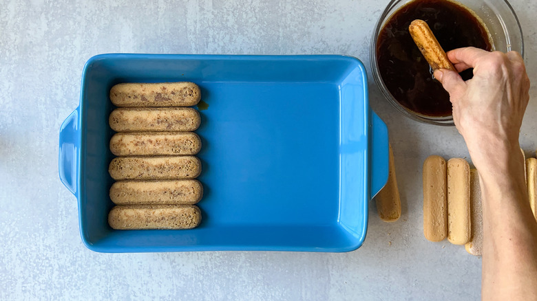 Dipping ladyfingers in espresso and placing in pan 