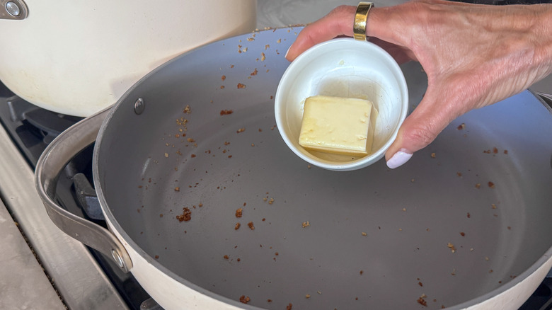 hand adding butter to skillet