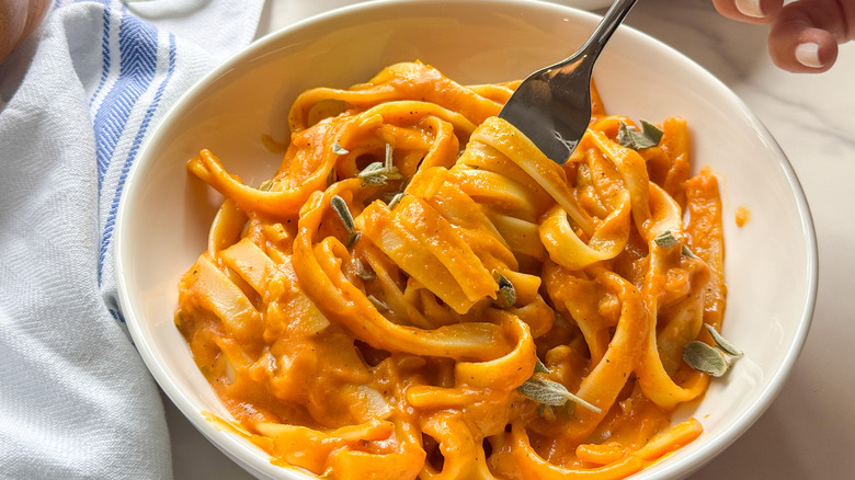 Fork twirling pumpkin pasta in bowl