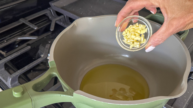 Small bowl of garlic going into saucepan