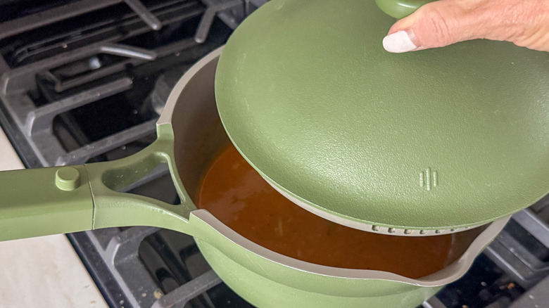 hand covering saucepan with lid