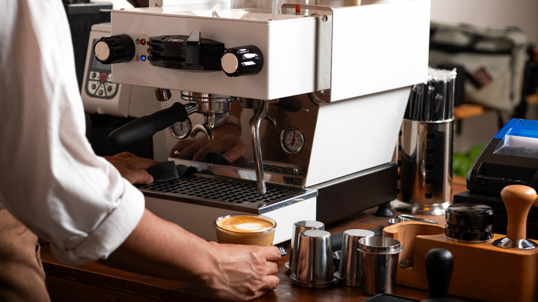 A person preparing a latte with a fancy espresso machine