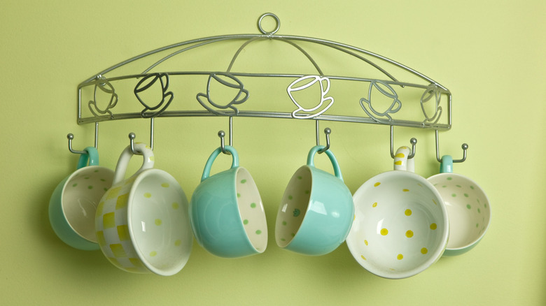 Yellow and blue coffee mugs hang from a coffee-themed wall hanger