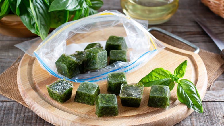 Basil ice cubes in a bag on a wooden cutting board