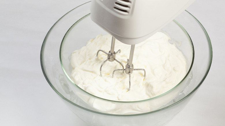 Making homemade whipped cream in a bowl with electric mixer
