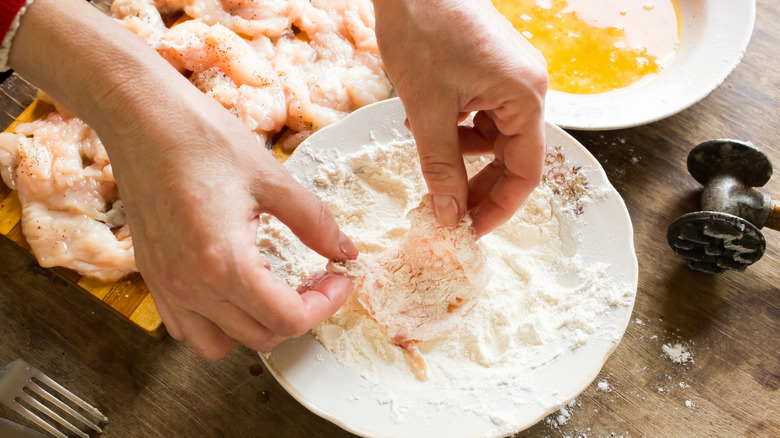 Person adding flour to chicken