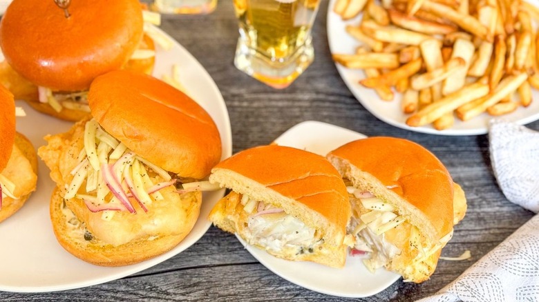 Crispy beer-battered fish sandwiches with fennel slaw on plates with fries and beer