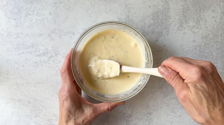 Mixing homemade tartar sauce in a glass bowl with rubber spatula